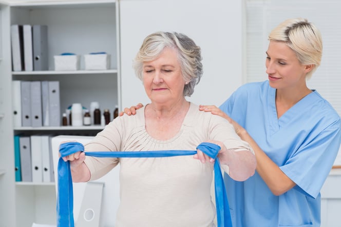 Physiotherapist guiding a patient through a resistance band exercise after breast cancer surgery